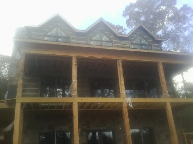 Dormers and porch framing on a large log home under construction — Roof Coating work by our crew in Kinderhook