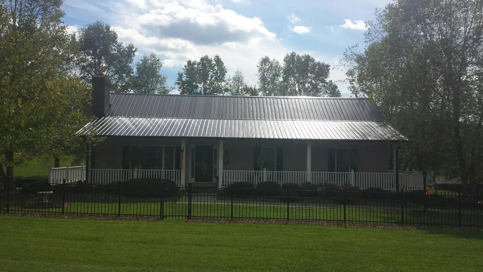 Gray metal roof on a brick ranch with a full width front porch — Gutter Guard Installation work by our crew in Kinderhook