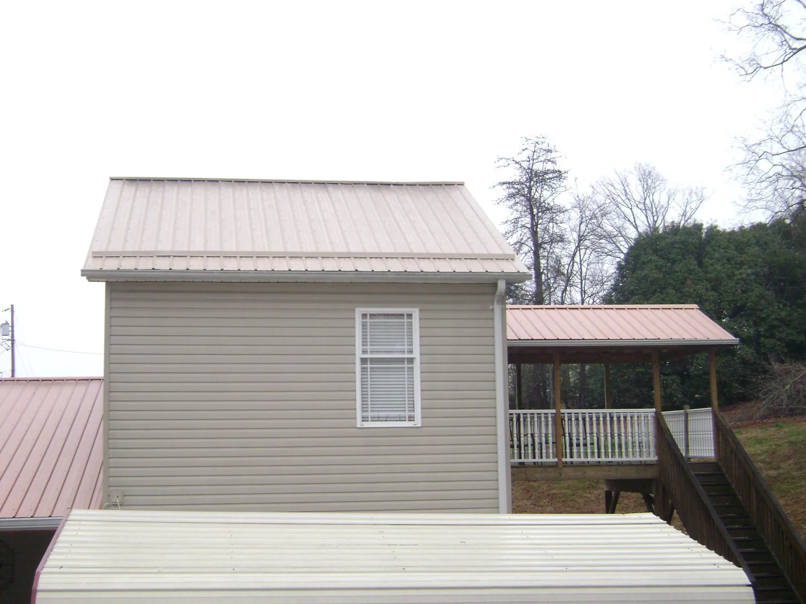 Tan metal roofs on a two story addition and attached porch, from a Roof Replacement job in Kinderhook