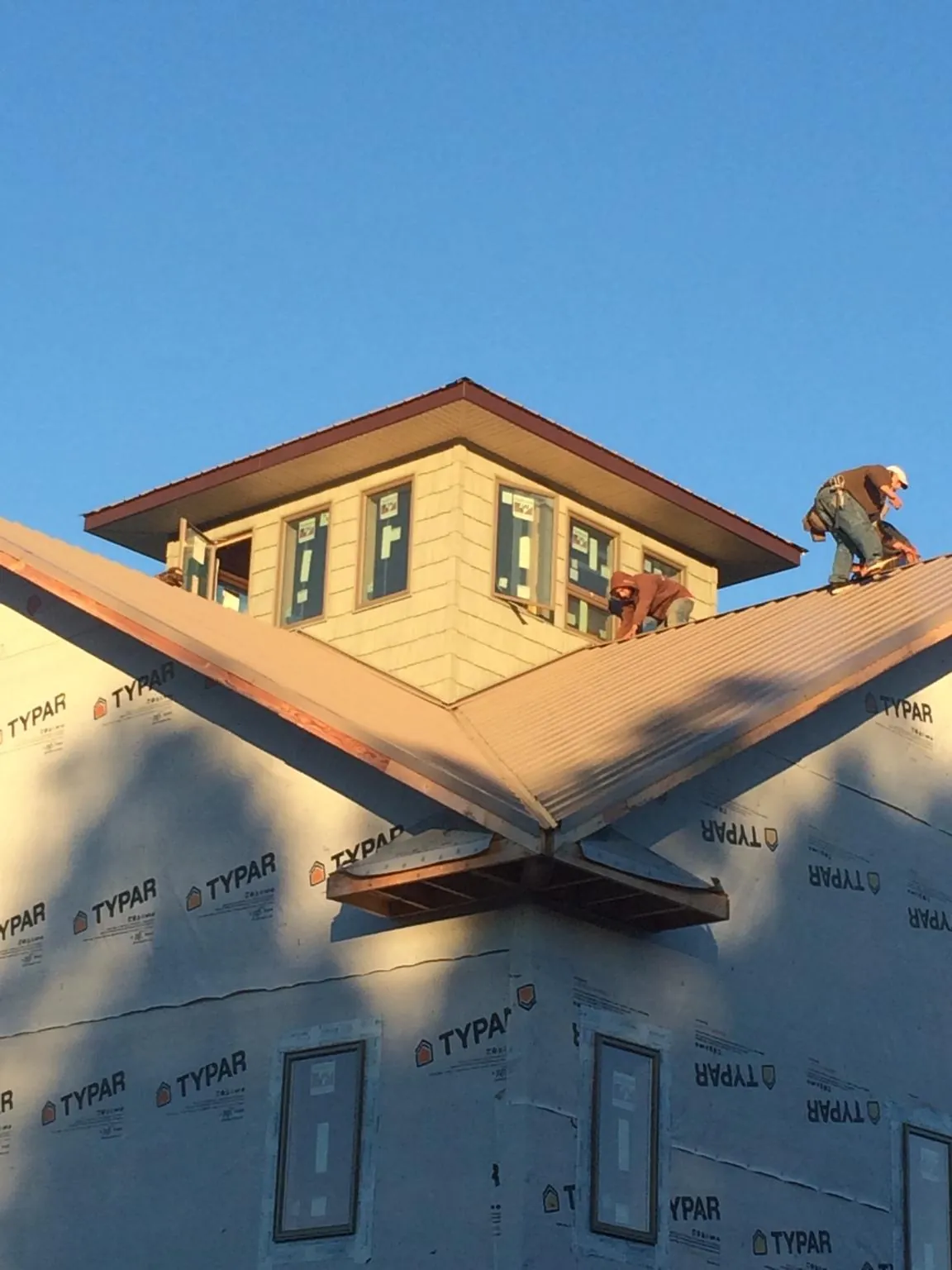 Roofers working around a rooftop cupola on a new metal roof at sunset — Roof Waterproofing in Kinderhook by Roofing Brothers